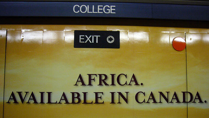 Wall shows COLLEGE and EXIT &rarr; signs and billboard copy reading AFRICA. AVAILABLE IN CANADA